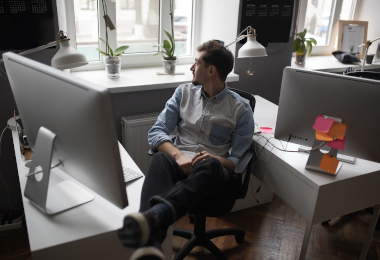 Young man thinking while looking through the window in a office