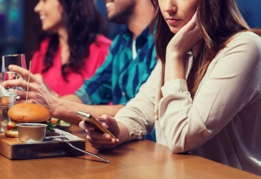 woman with smartphone and friends at restaurant